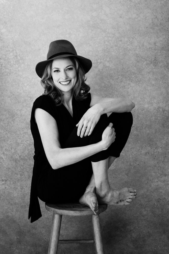 Woman sitting on a stool wearing a hat for boudoir photo
