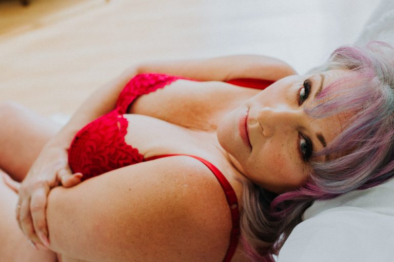 woman in red lace bra laying on back looking towards camera