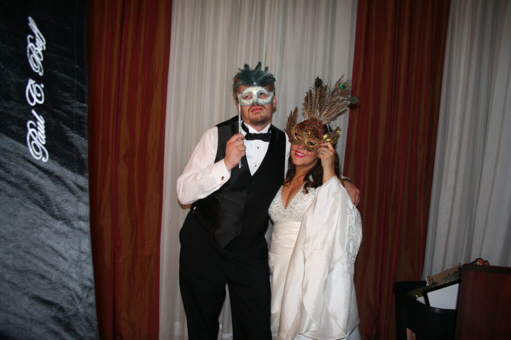 Bride and Groom holding masks over their faces