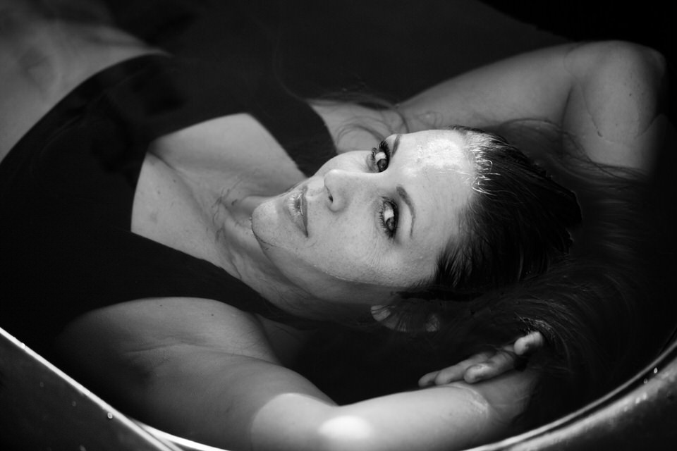 woman wearing a bikini laying in a tub of water