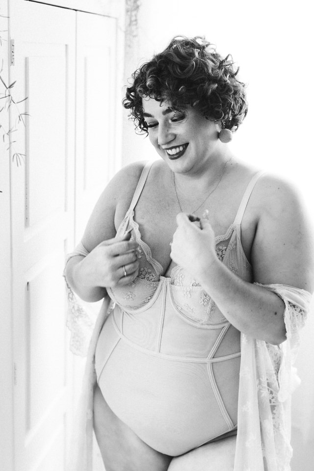 Boudoir image of beautiful and fat woman wearing lingerie and laughing