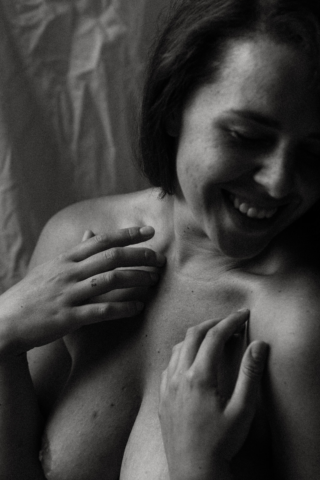 woman smiling with hands on her decolletage above naked breasts