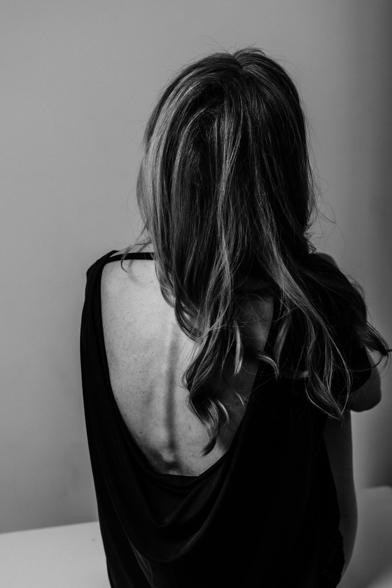 vancouver classy boudoir image of woman looking up and hair draped to one side of her back wearing open backless top
