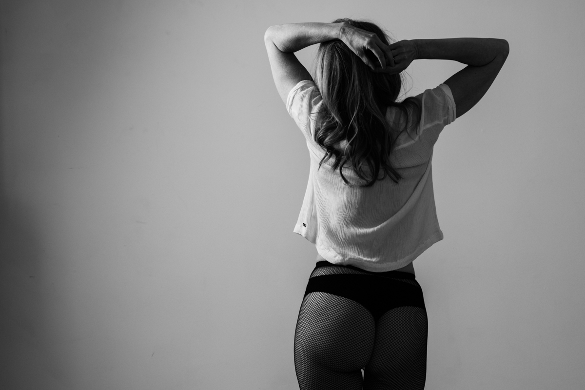 vancouver classy boudoir image of woman standing with back to camera wearing a loose top and panties with sheer stockings