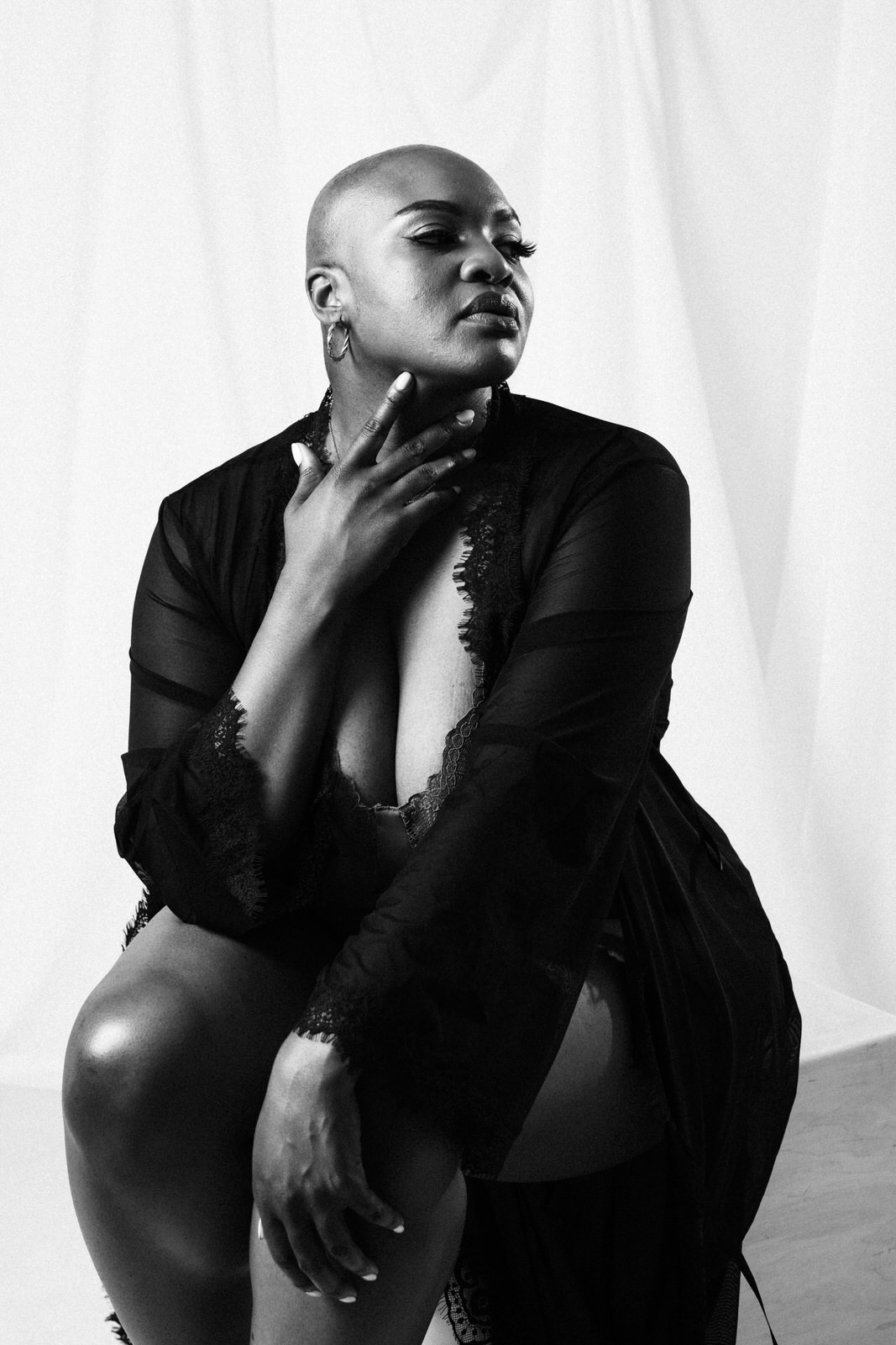 vancouver boudoir photographer image of plus size black woman with alopecia wearing lingerie and sitting with hand at neck
