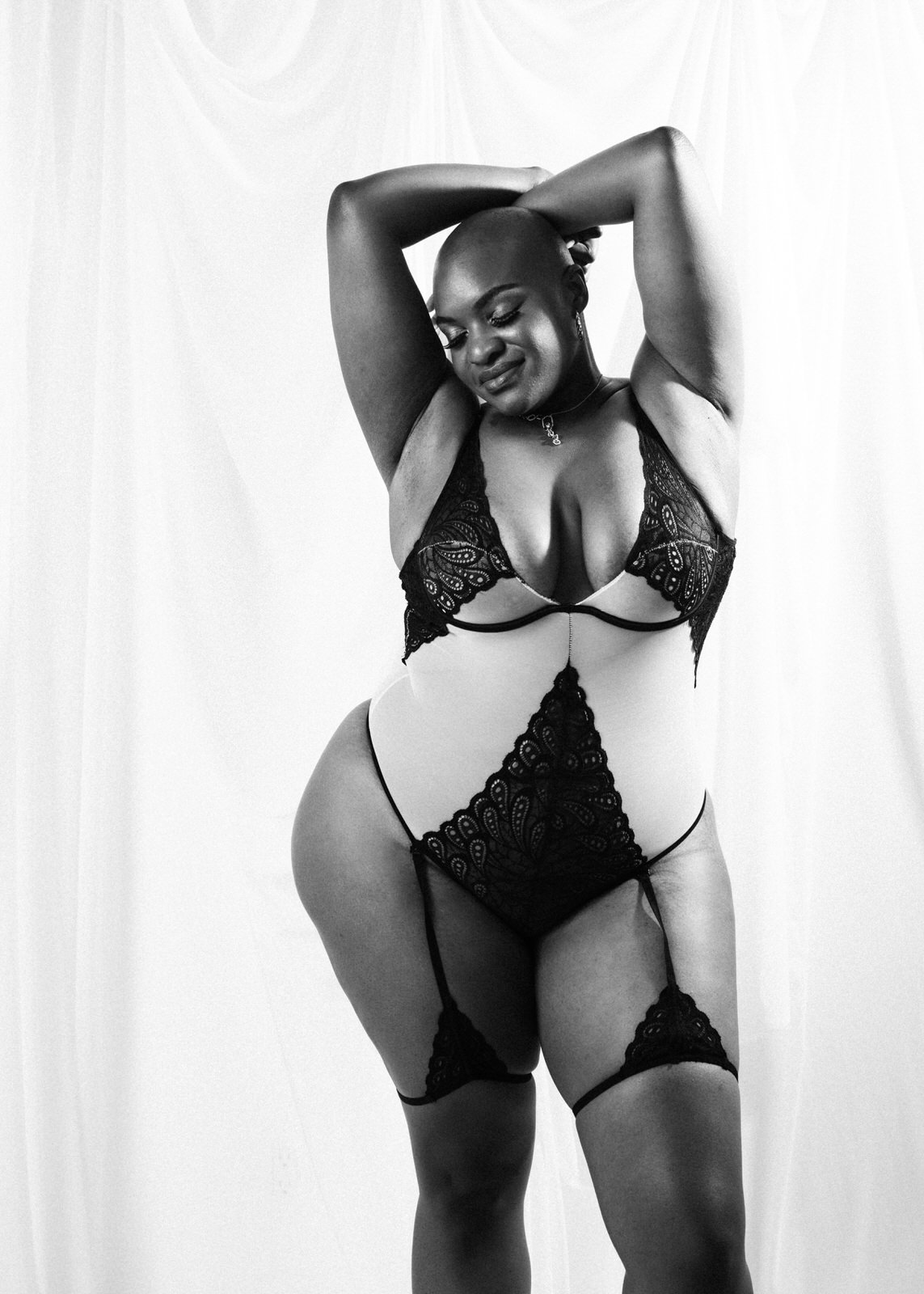 vancouver boudoir photographer image of plus size black woman with alopecia wearing lingerie and standing with hands up behind head