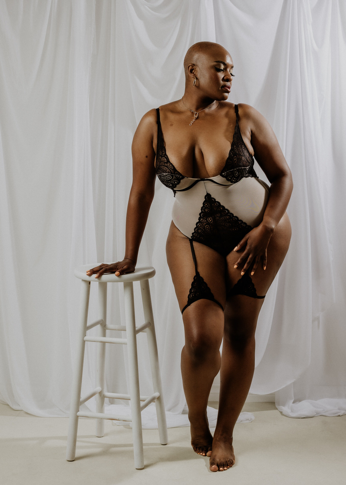 vancouver boudoir photographer image of plus size black woman with alopecia wearing lingerie and leaning on stool